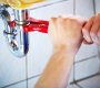 Hands using a wrench to tighten an under-sink pipe