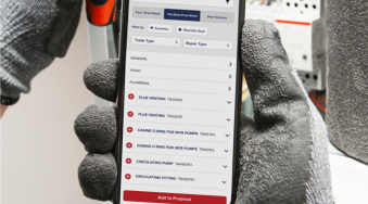 A person wearing protective work gloves is holding a mobile phone with a software platform pulled up. The screen is showing a flat rate pricebook that the worker can add items from in order to create a proposal for their customer.