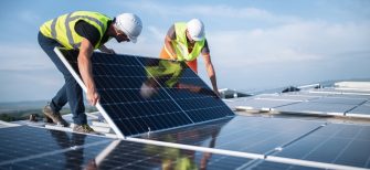 Two men on a roof, installing a solar panel