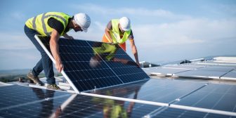 Two men on a roof, installing a solar panel