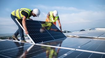 Two men on a roof, installing a solar panel