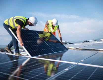 Two men on a roof, installing a solar panel