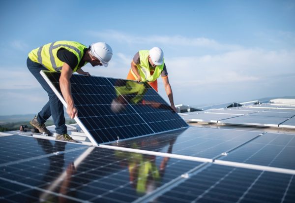 Two men on a roof, installing a solar panel