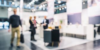 anonymous People standing and walking on a trade show booth, generic background with a blur effect applied