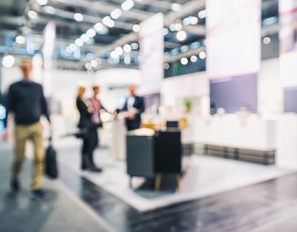 anonymous People standing and walking on a trade show booth, generic background with a blur effect applied