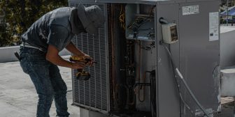 HVAC heating and cooling technician working on HVAC unit