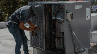 HVAC heating and cooling technician working on HVAC unit