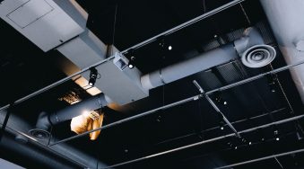 A low angle shot of a metal black ceiling with white ventilation pipes